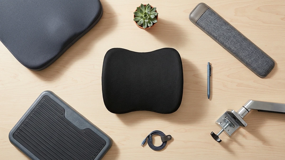 Flat-lay of ergonomic accessories including lumbar pillow, seat cushion, wrist rest, and footrest